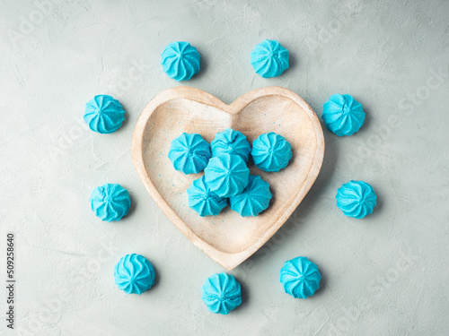 Fototapeta Naklejka Na Ścianę i Meble -  Heart shaped wooden dish with blue sweet meringues, flat lay
