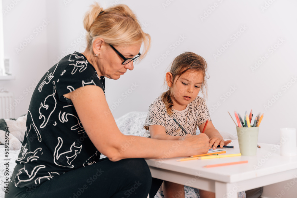 Mature woman granny with grandchild preschool girl drawing together at home. Mature woman granny with grandchild preschool girl drawing together at home.