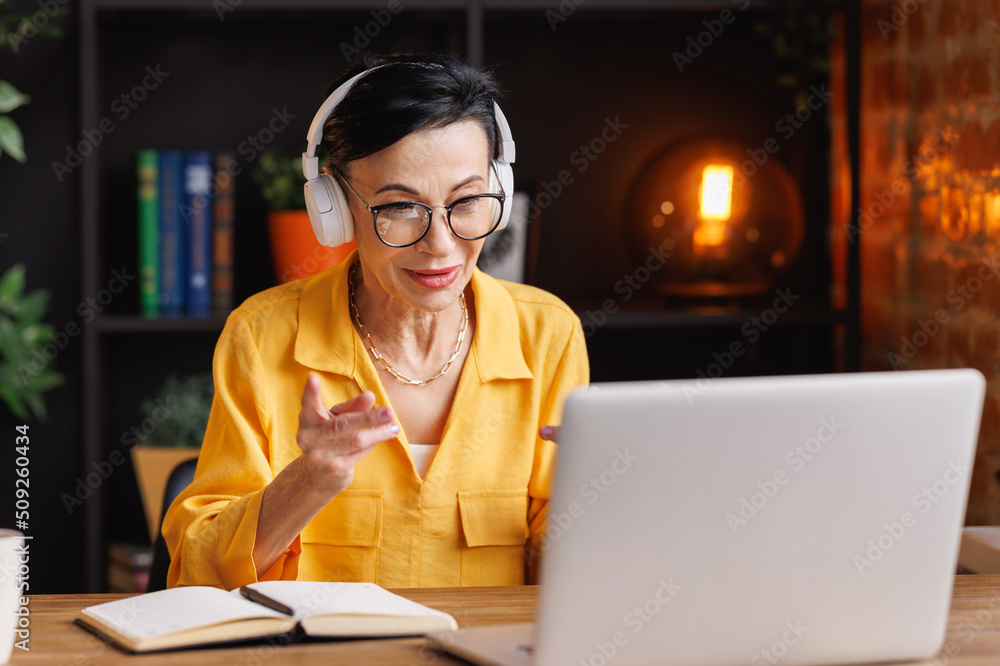© JenkoAtaman - Middle aged woman making video call in home office