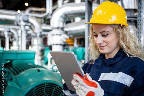Portrait of female industrial worker using her tablet computer in oil and gas production plant or refinery.