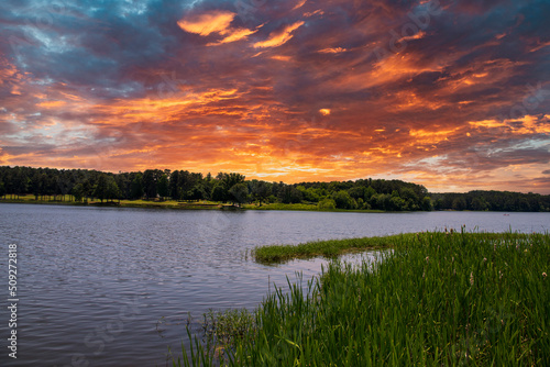 the vast blue waters of Lake Acworth surrounded by lush green trees, grass and plants with powerful clouds at sunset at Cauble Park in Acworth Georgia USA photo