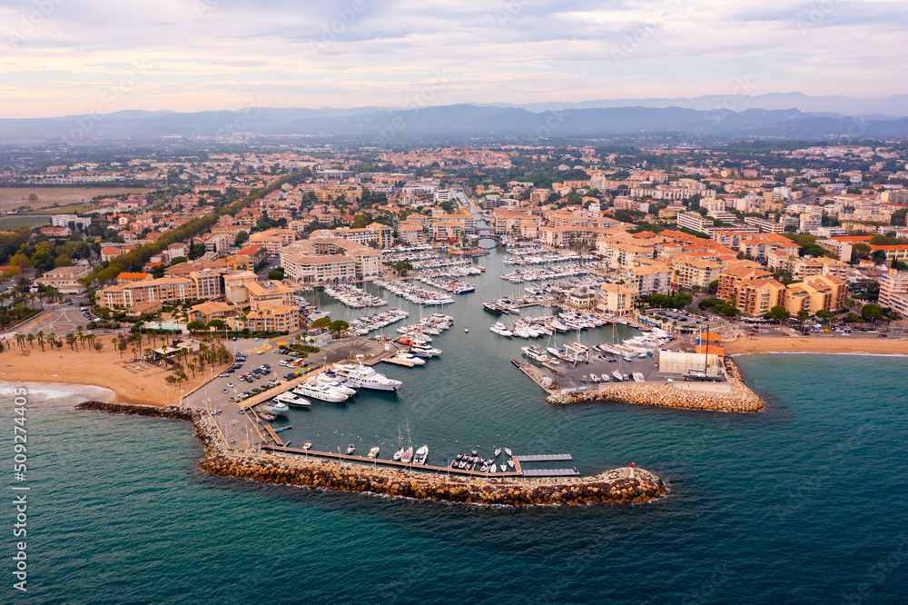 Scenic aerial panoramic view of modern Frejus cityscape on Mediterranean coast with sandy beach and marina on summer day, Var department, France