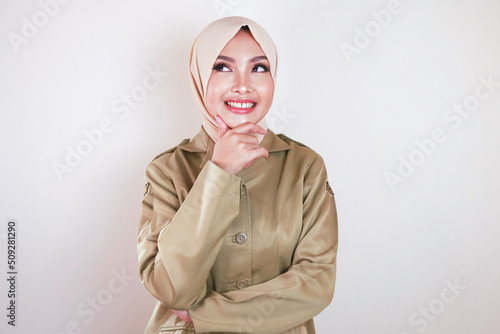 A young Asian Muslim woman wearing a brown uniform and hijab thinking a great idea photo