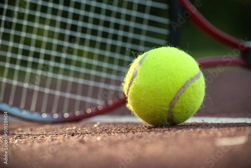 Yellow tennis ball near racquet and white line