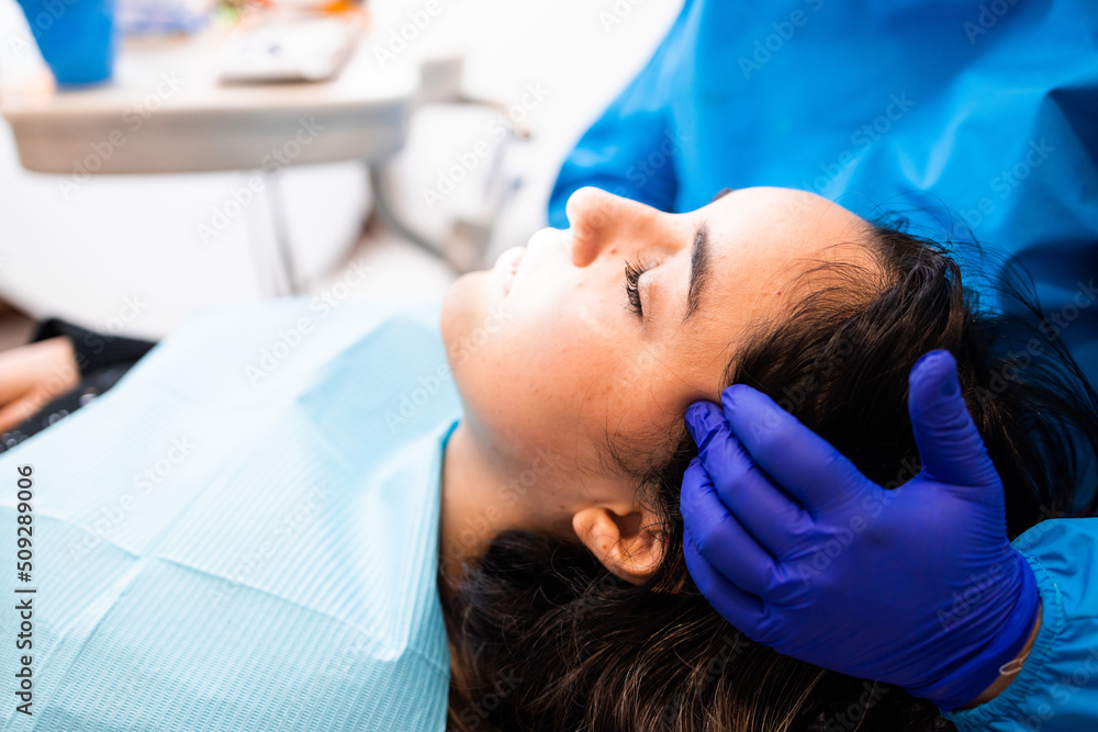 Unrecognizable dentist doing a palpation at the temporalis muscle. Exam to a female patient Unrecognizable dentist doing a palpation at the temporalis muscle. Exam to a female patient