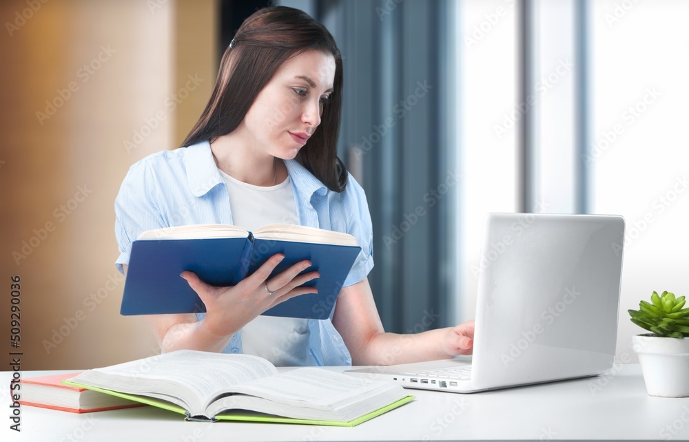 Young woman working at home with laptop and papers on desk Young woman working at home with laptop and papers on desk