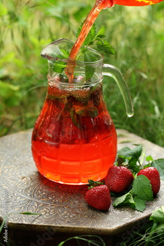 Homemade lemonade with strawberries and mint in the yard at the cottage