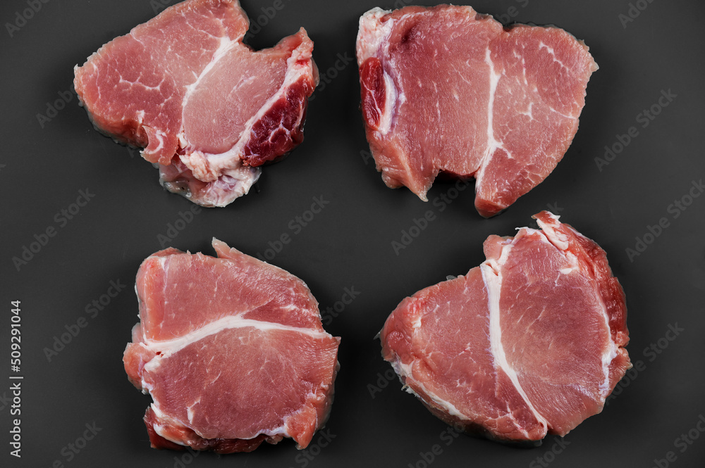 Raw pork against a gray background. Four portioned pieces of pork shoulder ready for further cooking or marinating. Food, ingredients. Selective Focus