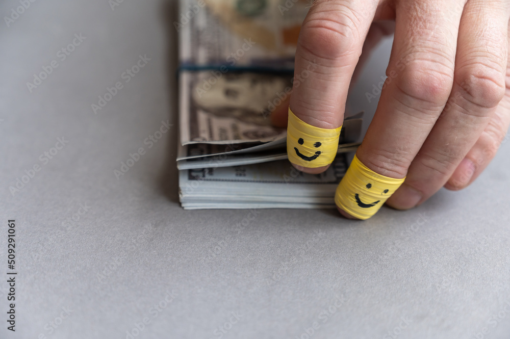 Man's fingers count money against gray background. Wad of American