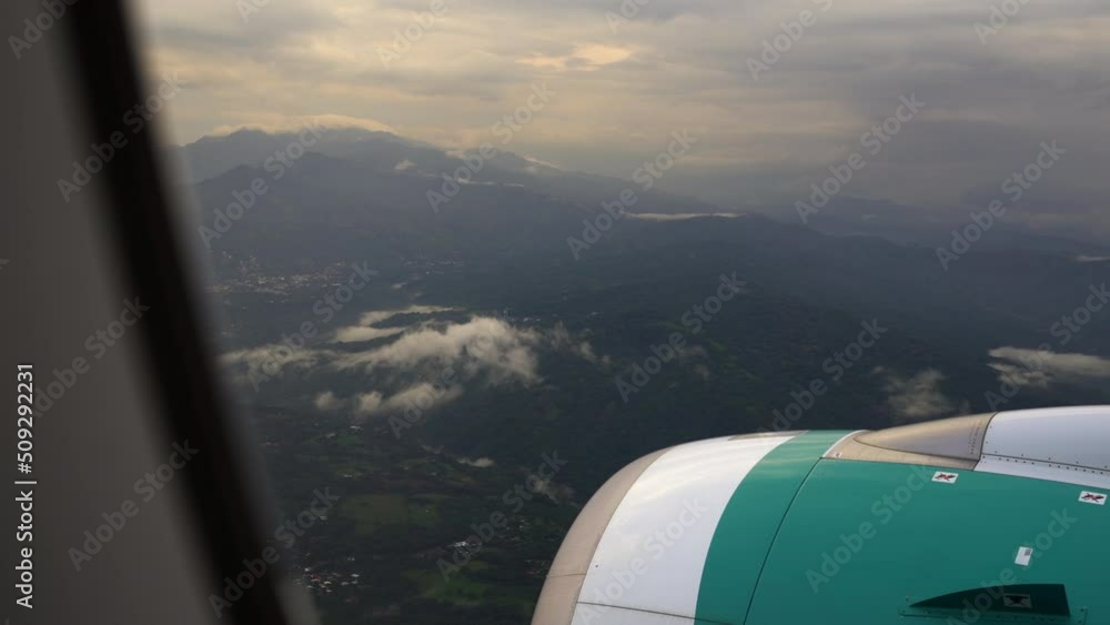 Airplane window scenic view of Costa Rica mountain landscape during scenic cloudy sunset, flight approaches travel destination of Central America Airplane window scenic view of Costa Rica mountain landscape during scenic cloudy sunset, flight approaches travel destination of Central America