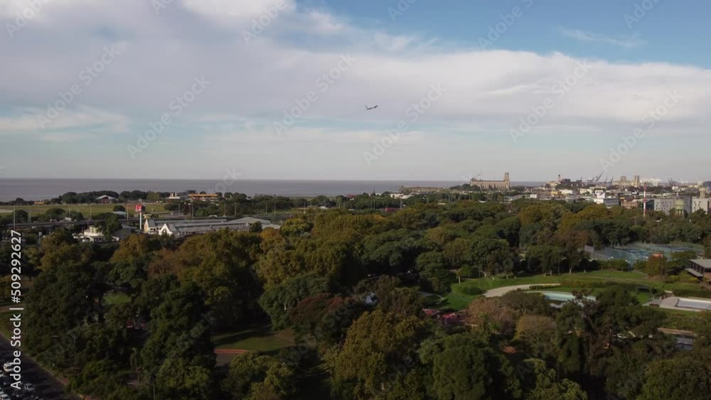 Drone flying over Palermo park with airplane taking off in background. Aerial forward Drone flying over Palermo park with airplane taking off in background. Aerial forward