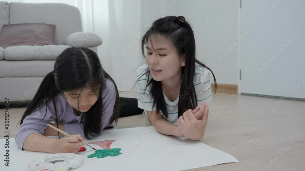 Mother add a new activity to enhance the development of children. family activities. A mother is encouraging her daughter to draw her first picture .on a family holiday. Mother add a new activity to enhance the development of children. family activities. A mother is encouraging her daughter to draw her first picture .on a family holiday.