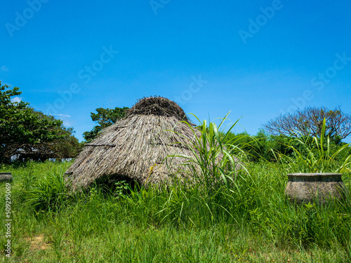 晴れた日の沖縄県うるま市伊計島にある茅葺き屋根が再現された仲原遺跡