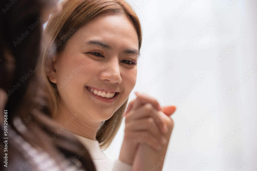 Happy LGBT lesbian couple holding hands sitting on bed hand by hand - same-sex lesbian couple and female friendship and love. Happy LGBT lesbian couple holding hands sitting on bed hand by hand - same-sex lesbian couple and female friendship and love.