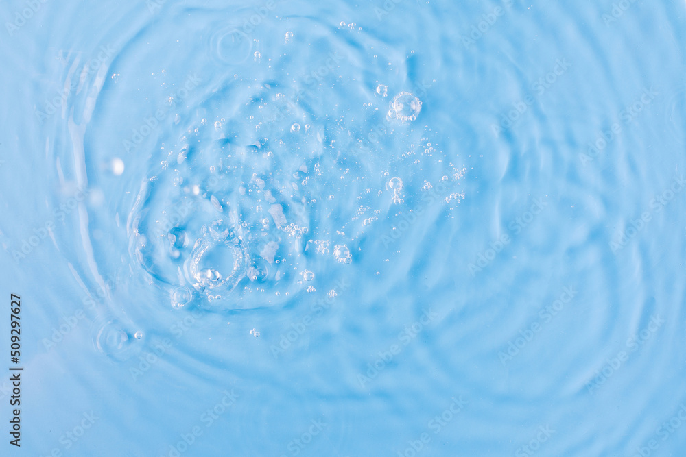 Drops fall down into clear fresh water on light blue background view from above Drops fall down into clear fresh water on light blue background view from above