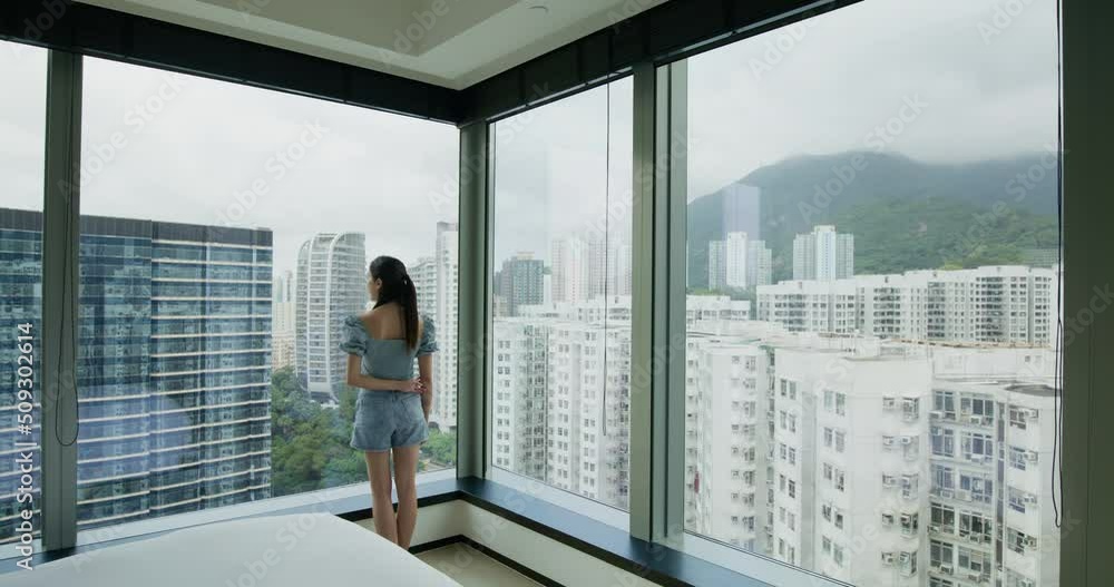 Woman stand in front of the window and look outside the city Woman stand in front of the window and look outside the city