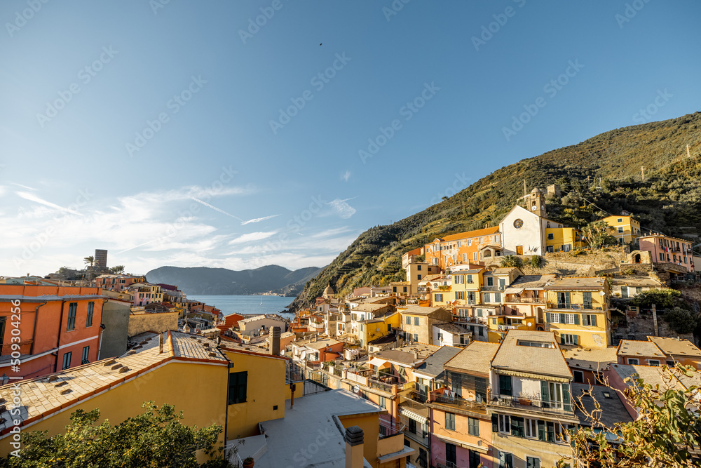 Landscape of Vernazza village with colorful old houses and church on the hill at sunny day. Famous village at Cinque Terre National Park at coastline in northwestern of Italy