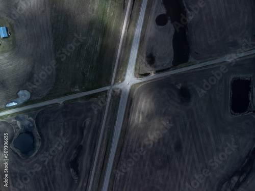 Overhead view of highway intersection dappled in sunlight as car passes underneath