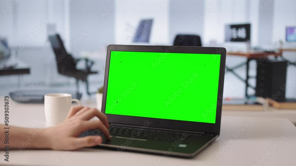 Close up of young man typing non-stop on keyboard of modern laptop with empty green screen. Male employee working on new marketing strategy at bright office. Close up of young man typing non-stop on keyboard of modern laptop with empty green screen. Male employee working on new marketing strategy at bright office.