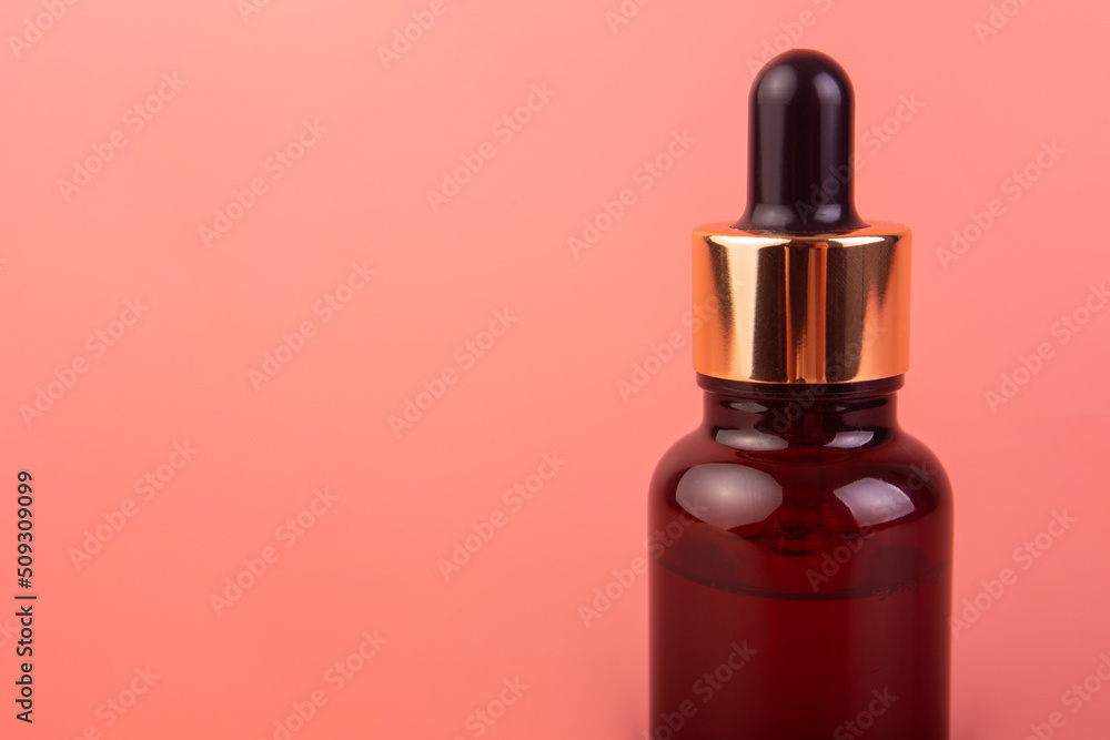 Brown bottle with dropper with a beauty serum on pink background. Glass packaging for cosmetic product, essential aroma oil. Skin care, hydration and nutrition with collagen. Brown bottle with dropper with a beauty serum on pink background. Glass packaging for cosmetic product, essential aroma oil. Skin care, hydration and nutrition with collagen.