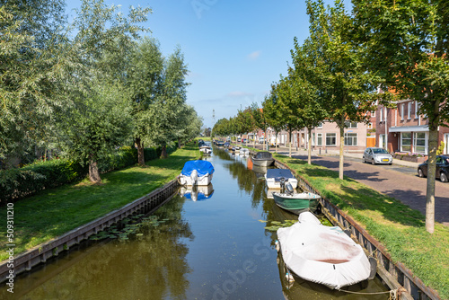 Small boats moored in a canal on the Zandslootkade in the South-Holland village of Sassenheim. Taken in the direction of the van den Berch van Heemstedeweg in Teylingen in the Netherlands. photo