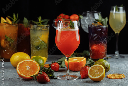 Colorful refreshing drinks for summer, cold strawberry lemonade juice with ice cubes in the glasses garnished with sliced fresh lemons