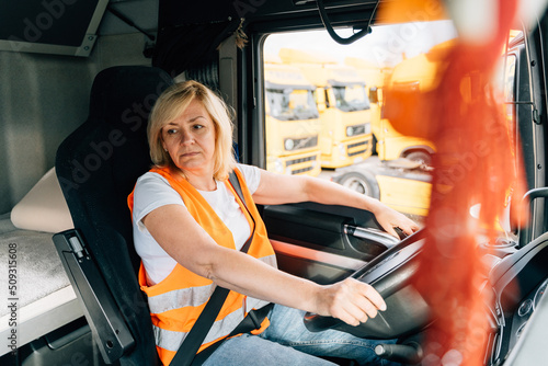 Mature woman truck driver steering wheel inside lorry cabin. Happy middle age female trucker portrait  photo