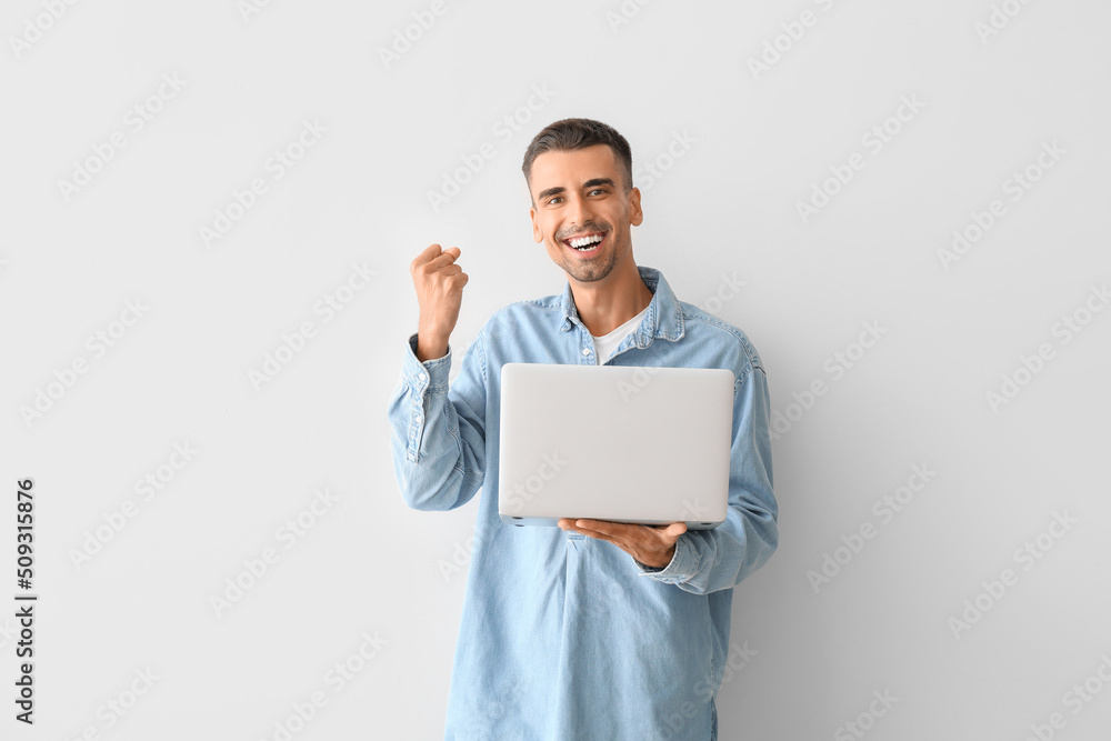 Happy young man using laptop on light background Happy young man using laptop on light background