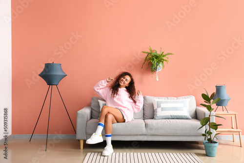 Young woman relaxing on comfortable sofa near pink wall