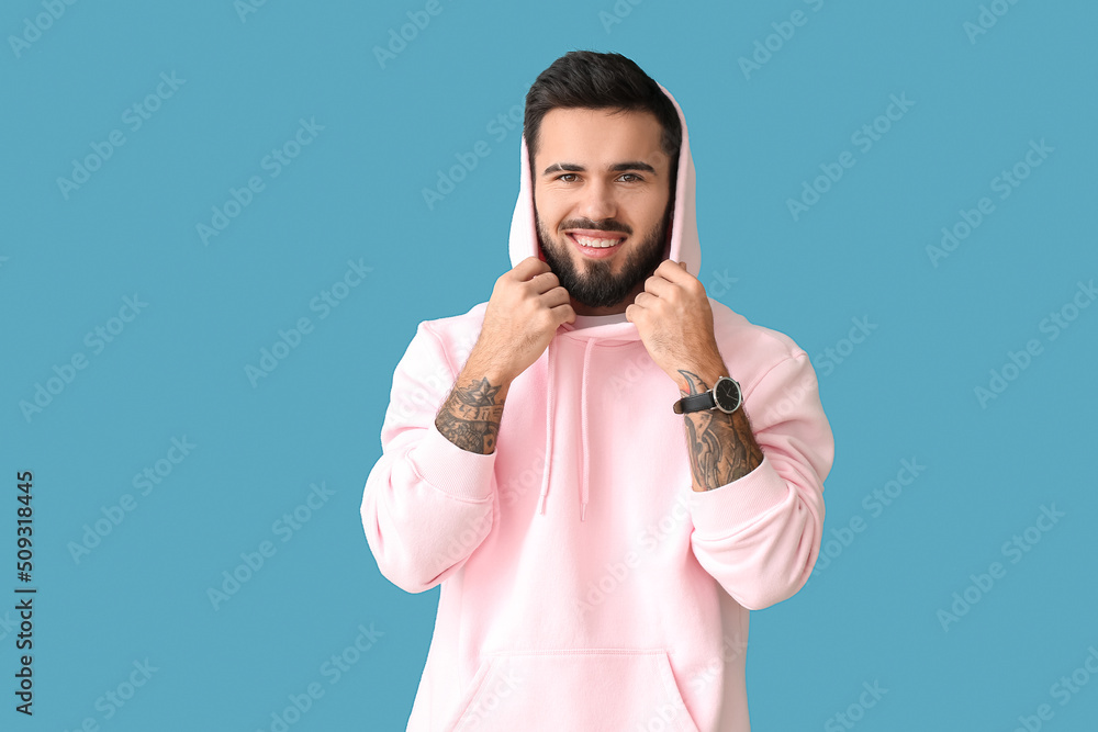 Young bearded man wearing stylish hoodie on blue background Young bearded man wearing stylish hoodie on blue background