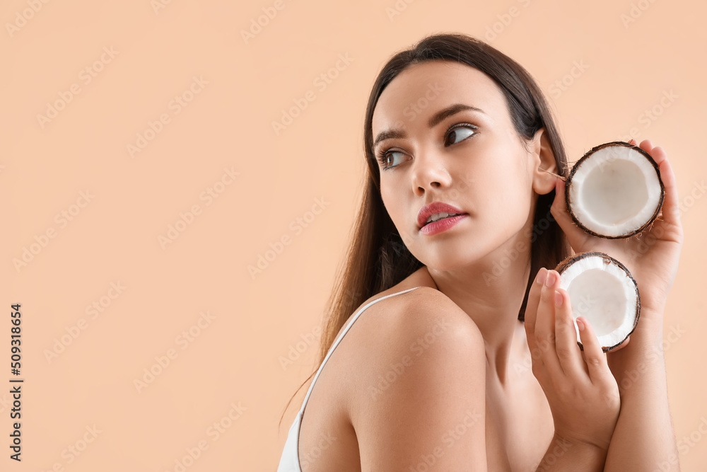 Young woman with coconut on beige background Young woman with coconut on beige background