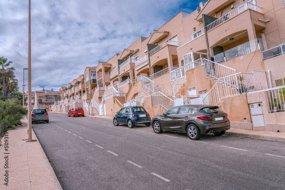 Modern residential street in Torrevieja with typical houses, vacation homes. Few cars parked. Spain