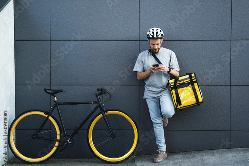 Foto Express food delivery courier with insulated bag looking at phone