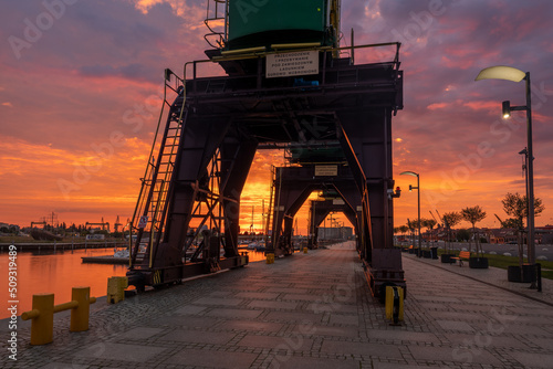 Historic harbour cranes on riverside boulevards in Szczecin during a dramatic sunrise