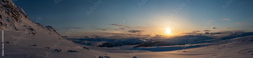 Panoramic sunset, golden light over Norwegian snowy winter mountains. Joesjo, Sweden