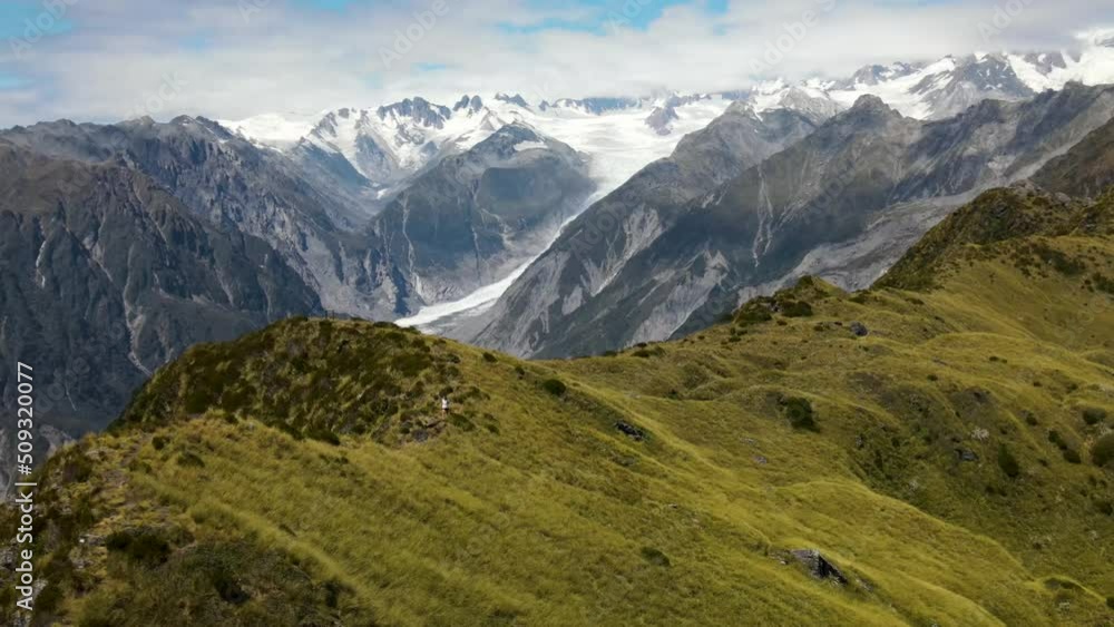 Traveler walking alone on mountain ridge in beautiful New Zealand mountains. Challenging hike, traveling - aerial drone