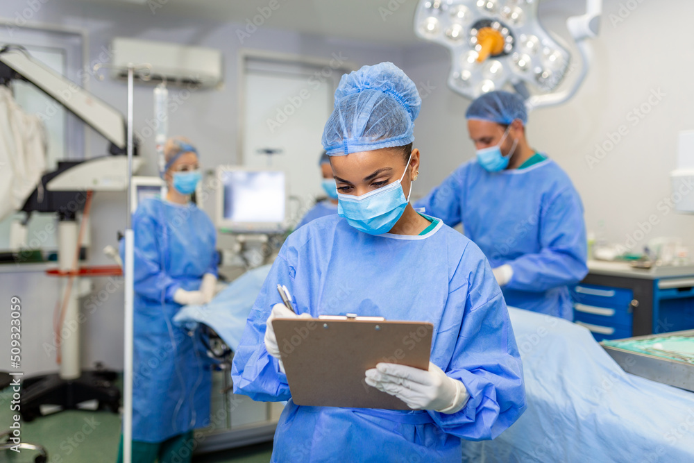 Surgeon writing on clipboard in operation room, anaesthesiologist writing the updates Surgeon writing on clipboard in operation room, anaesthesiologist writing the updates