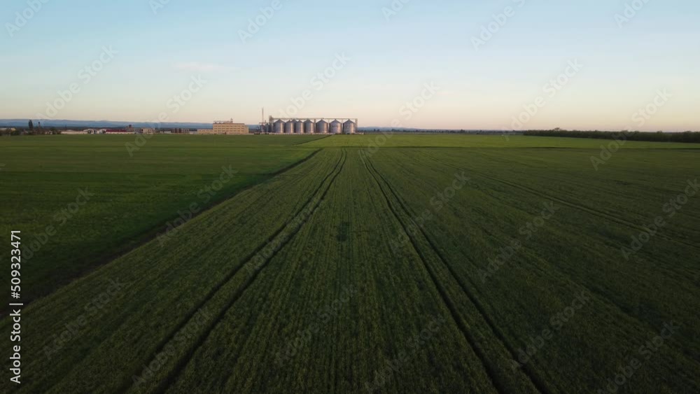 Grain elevator. Metal grain elevator in agricultural zone. Agriculture storage for harvest. Grain silos on green nature background. Exterior of agricultural factory. Nobody. Grain elevator. Metal grain elevator in agricultural zone. Agriculture storage for harvest. Grain silos on green nature background. Exterior of agricultural factory. Nobody.