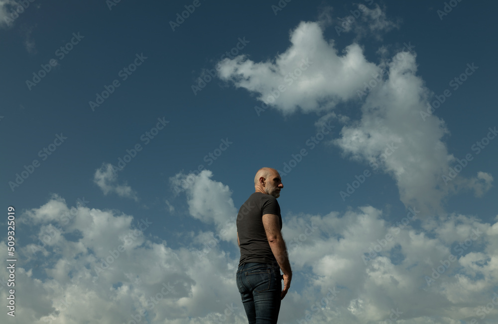 Low angle view of adult man against cloudy sky Low angle view of adult man against cloudy sky