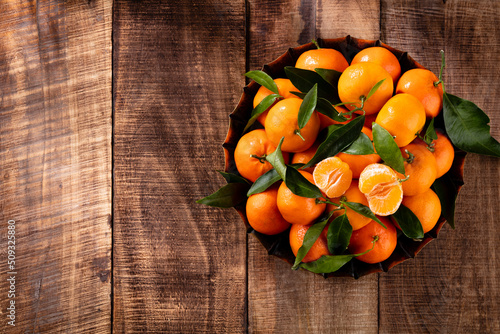 Fresh mandarin oranges fruit or tangerines with leaves in wooden box, top view