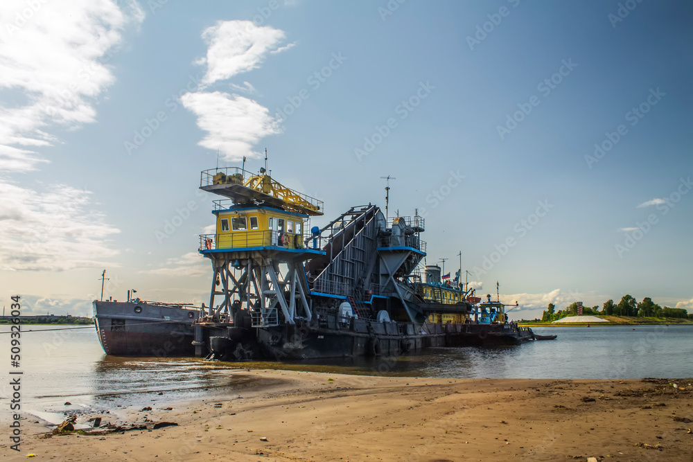 Fototapeta premium A floating dredger in action. Extracts and drains sand into a special barge. A sunny summer day.
