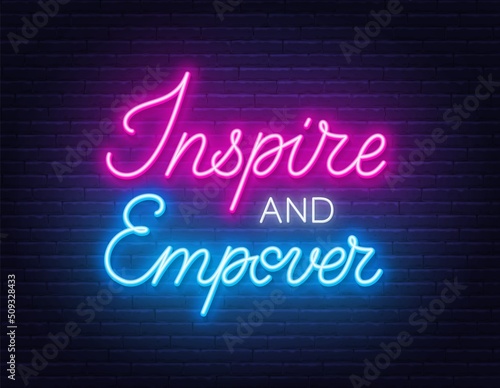 Inspire and Empower neon sign on brick wall background.