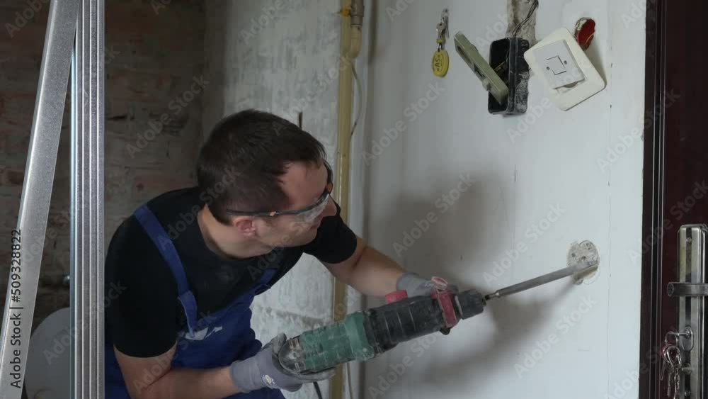 Worker drilling a hole in a wall using drilling machine Worker drilling a hole in a wall using drilling machine