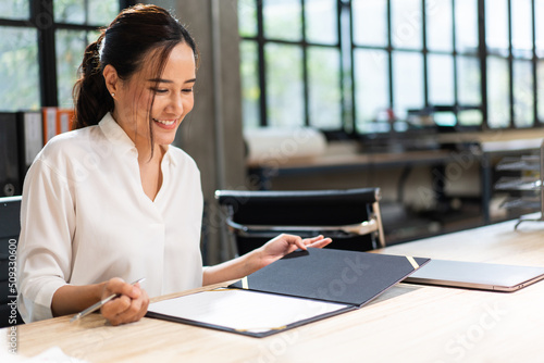 Canvas Print Asian business female project manager reading document report at desk in the office