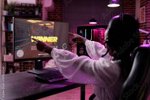 Fototapeta Woman streamer playing video games tournament on computer, celebrating win