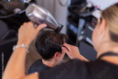 Drying hair at beauty salon. Stylist busy with work. Closeup.