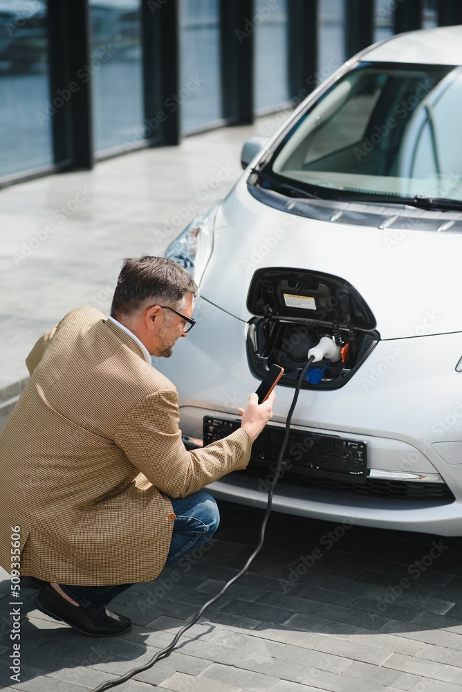 Man holding power connector for electric car