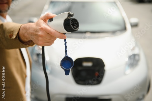 Man charges an electric car at the charging station