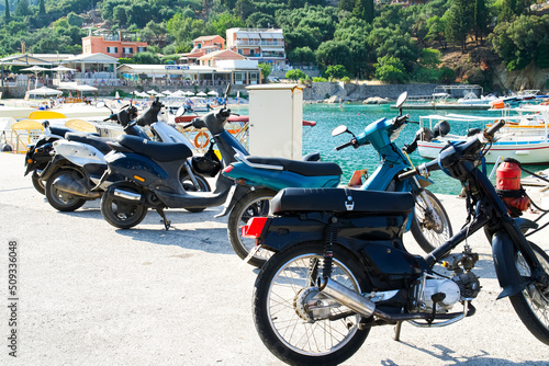 Parked mopeds on the seashore, waiting for people. People left mopeds and went to the sea.