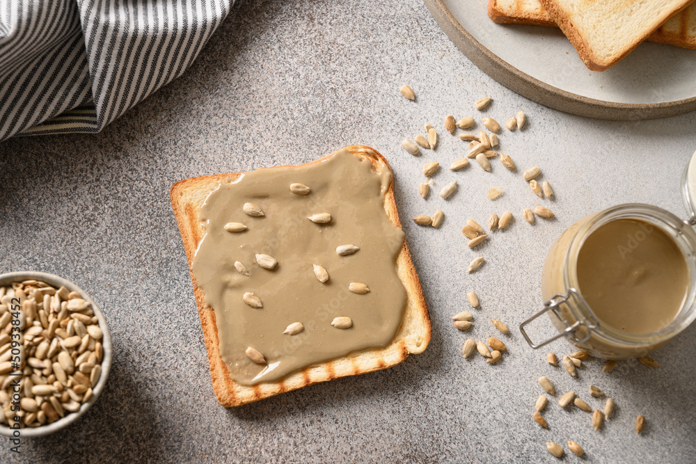 Crispy bread with Sunflower seed butter on gray background. Cooking allergy-friendly breakfast. View from above. Crispy bread with Sunflower seed butter on gray background. Cooking allergy-friendly breakfast. View from above.